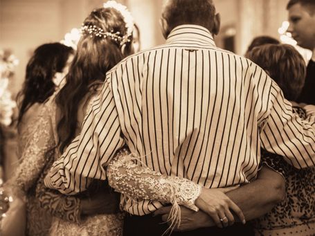 Familie Braut Vater Mutter umarmen sich auf Hochzeit der Tochter und tanzen gemeinsam