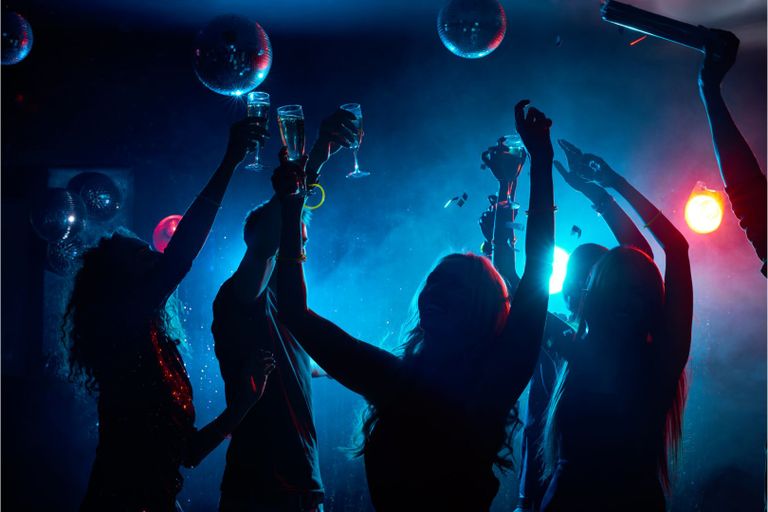 Tanzende Frauen und Männer in Partybeleuchtung Nebel Sektgläser Diskokugeln Geburtstag